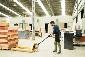 Male carpenter loading a pallet jack with wood boards