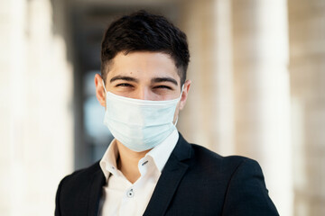 portrait of a student manager in a mask from coronavirus, pandemic, epidemic, virus. He was wearing a black business suit and a white shirt. works as a manager in a bank. the European appearance.