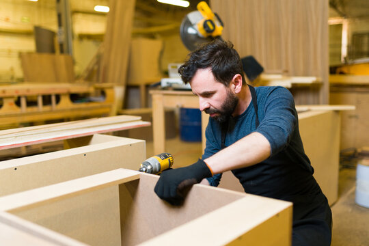 Hispanic man in his 30s doing woodworking in his workshop
