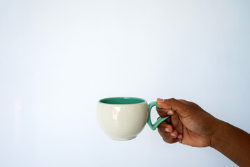 The hand of a dark-skinned man holds a disposable cup for coffee