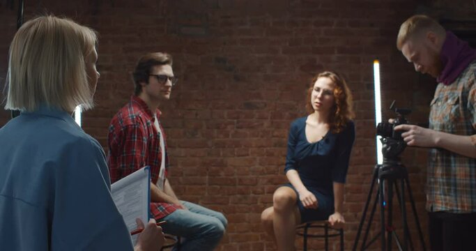 Woman director talking to host and guest in studio before filming interview