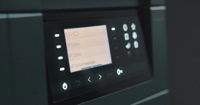 Close up of woman setting program on control panel of washing machine