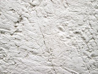 A crack in a white rough wall. Stock photo destruction of textural surface.