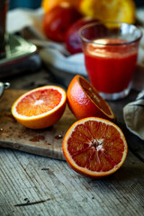 Blood orange halves with fresh juice in glasses on background on wooden table.