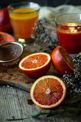 Blood orange halves with fresh juice in glasses on background on wooden table.