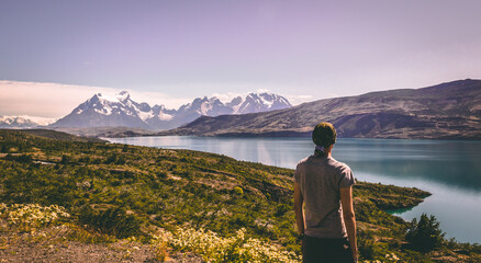 Fototapeta premium Person standing viewing a lake and mountains with snow from a hill. Torres del Paine national park, Patagonia, Chile, South America