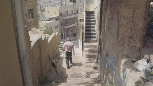 Following man through narrow street with steps and graffiti in the Middle East 