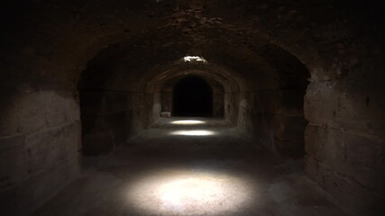 Fototapeta na wymiar Pass through a long and dark Roman basement. Basement under the amphitheater in El Jem, Tunis. Ancient roman building. The camera is approaching