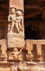 Aihole, Karnataka, India - November 7, 2013: Durga Gudi or Temple. Closeup of damaged red stone pillar with male-female sculpture.