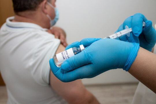 Taking COVID-19 vaccine into syringe. Doctors create invent coronavirus vaccine. The hand of medical staff in blue sterile gloves hold ampoule, medicine for pandemic applied. 