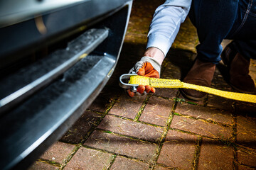 A male hand attaching a towline to a car.
