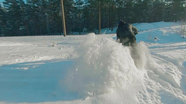 Cyclist in Black Clothes, Helmet and Snow Glasses Riding on Electric Bike in the Snow in Winter Forest. E-Bike Riding and Drifting at Cold Sunny Day - Super Slow Motion
