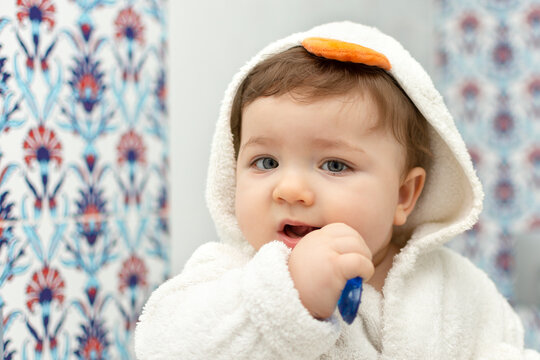 Portrait of cute baby boy with tooth brush. Child brushing teeth. Teeth health care. Real people in real interior. Toddler and first tooth morning hygiene. Kid in duck bathrobe.