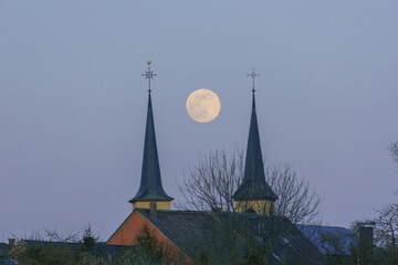 Fototapeta premium Full moon in between two church towers in the blue evening sky