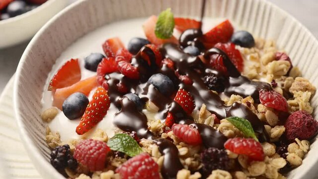 Granola with berries topped with chocolate sauce, healthy breakfast. Very close-up 