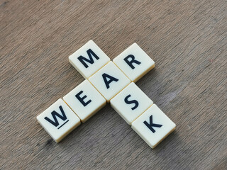 Side view WEAR MASK crossword by square letter tiles against wooden background.Medical concept.