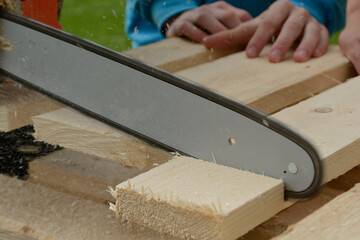 Person Cuts Wood Board With Chainsaw