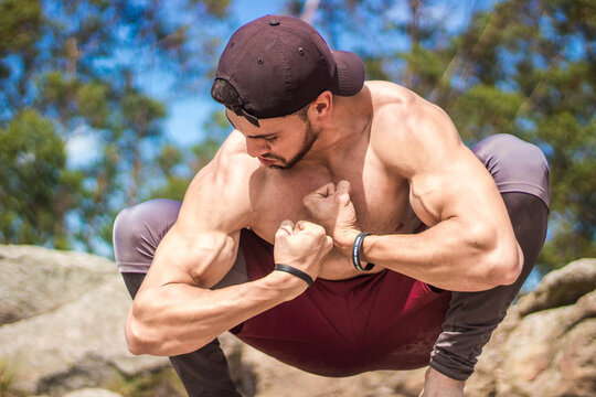 Powerful masculine young sportsman showing muscules of his biceps during training in nature