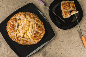Grain bread, cut in the center to put the fondue cheese, on black plates and a quarry background. 2
