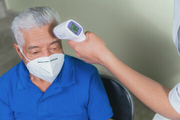 Senior man on medical check-up checking his temperature