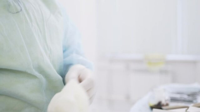 Close up of a nurse taking a sterile glove in the hospital. Action. Preparation for the surgery in the operating room, concept of medicine.