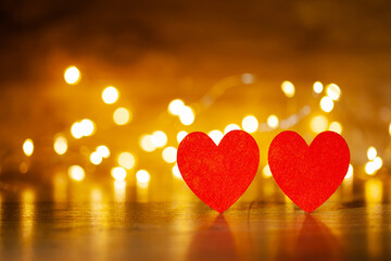 in the foreground are two krvs hearts, in the background on a wooden backdrop of a glowing garland