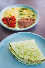 plant-based food, vegan version fo the viral layered tortilla wrap hack with red peppers grated dairy-free cheese avocado and refried beans