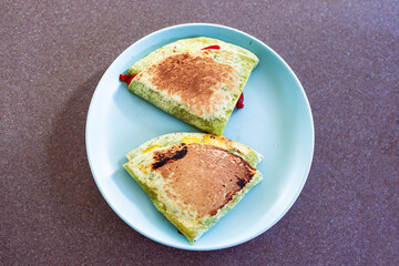 plant-based food, vegan version fo the viral layered tortilla wrap hack with red peppers grated dairy-free cheese avocado and refried beans