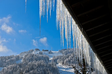 Icicles Hanging Down From A Roof Against A Winterly Mountain Scenery, Morzine, Haute-Savoie, FRance