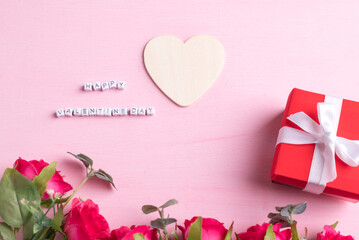 Beautiful red rose flower bouquet with gift box and happy valentine day alphabet with heart shape on pink background