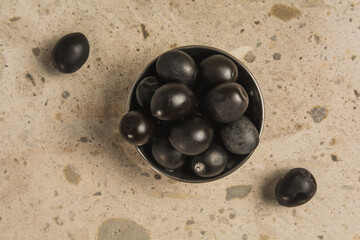 Stuffed black olives, in a black plate on a stone background. 