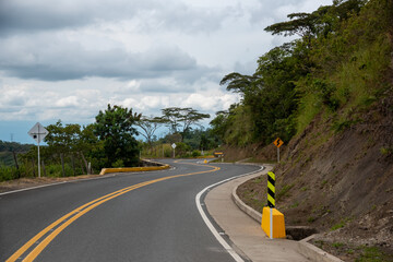Rural road with curves and signs in a warm climate zone in Colombia.