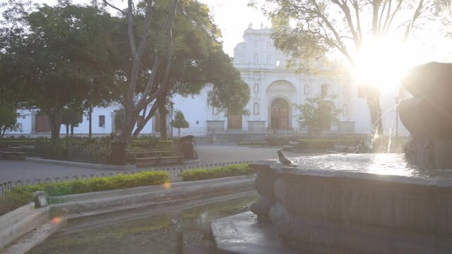 Sunrise at Mermaids Fountain in the central park of Antigua Guatemala - pigeons flying over beautiful colonial park with a fountain in Antigua Guatemala 