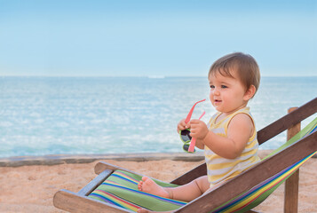 Baby in a deck chair by the sea.