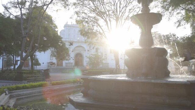 Sunrise at Sirens Fountain in the central park of Antigua Guatemala - pigeons flying over beautiful colonial park with a fountain in Antigua Guatemala 