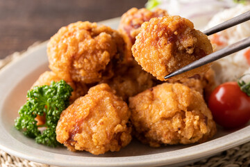 箸で挟んだ唐揚げのアップの写真