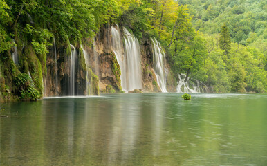 Fototapeta na wymiar long exposure wide shot of a waterfall and lake at plitvice lakes national park on a rainy spring day