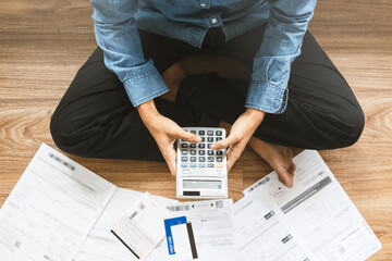 Top view man sitting on the floor stressed and confused by calculate expense from invoice or bill, have no money to pay thinking of taking the house to mortgage causing debt, bankruptcy concept.