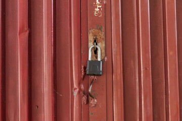 Red metal door closed on the lock corrugated steel fence gate padlock garage shed in Sofia, Bulgaria, Eastern Europe