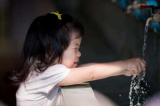 Asian little kid girl is trying to wash her hands to keep her hands clean and without germs for good health. Baby age 3 years old.