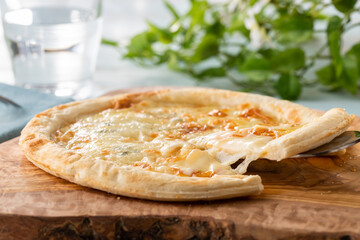 ピザサーバーで持ち上げられた、とろーりチーズのピザ