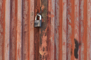 Red metal door closed on the lock corrugated steel fence gate padlock garage shed in Sofia, Bulgaria, Eastern Europe
