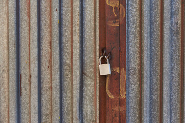 Fototapeta na wymiar Aged metal door closed on the lock corrugated steel fence gate padlock garage shed in Sofia, Bulgaria, Eastern Europe