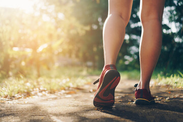 Woman wear running shoe on to walking and running on nature green background.Health exercise.