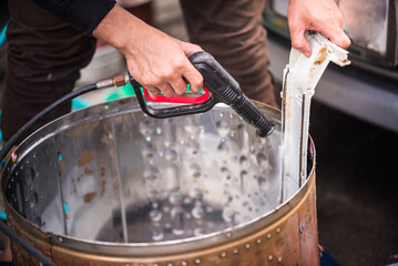 Asian man's hand held a high-pressure spray gun was spraying water onto the stain with the...