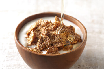 はちみつを注いでいる朝食のシリアル