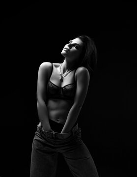 Black and white portrait of excited sexy woman in black underwear lingerie stands with her head up holding hands down in pants touching herself feeling pleasure bliss. Beauty of woman body concept