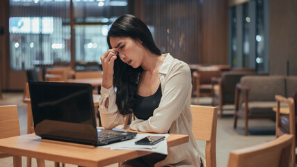 Fototapeta premium Serious woman working on laptop late at night. Asian Businesswoman working hard and overtime in office.
