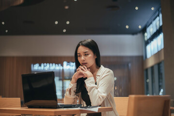 Serious woman working on laptop late at night.  Asian Businesswoman working hard and overtime in office.