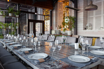 Modern veranda restaurant interior, banquet setting, glasses, plates